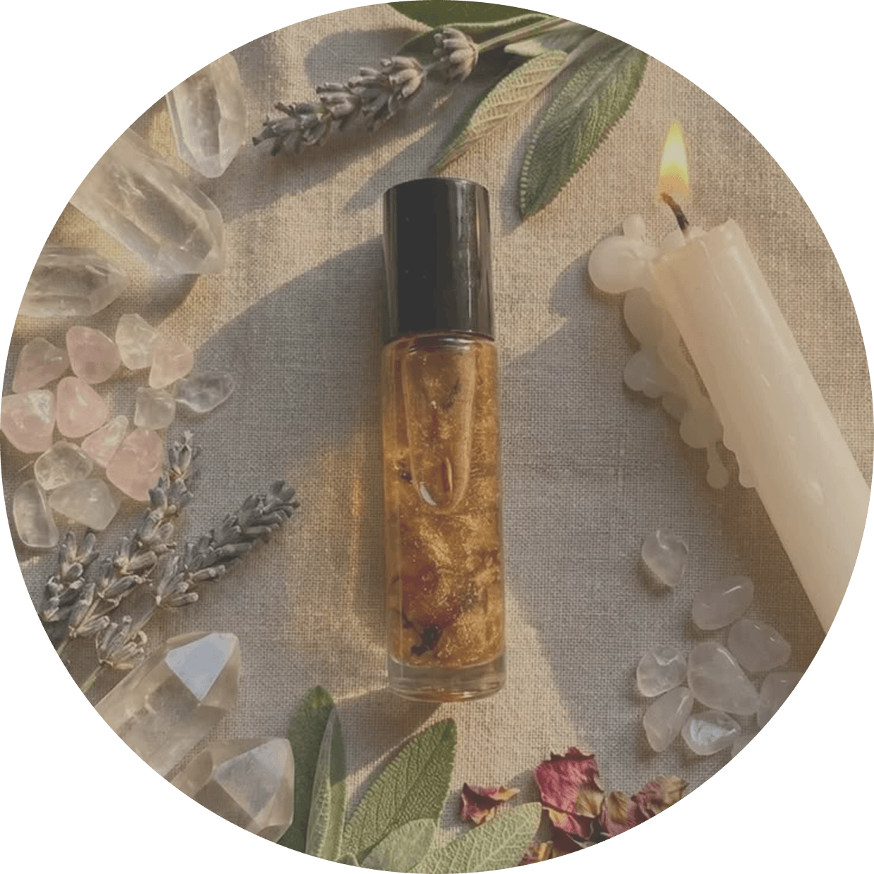 A golden aromatherapy roller surrounded by herbs, crystals and candles