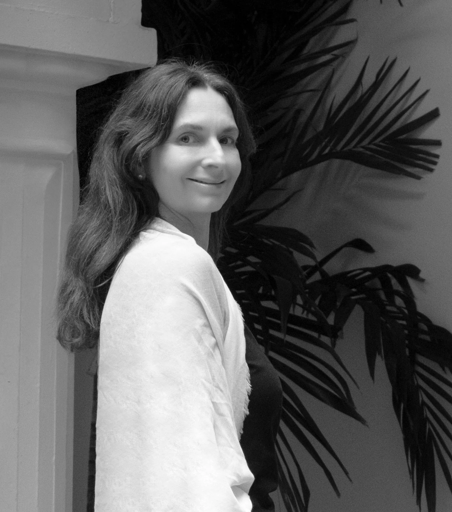 A black-and-white portrait of Gabi in front of large leafy plants