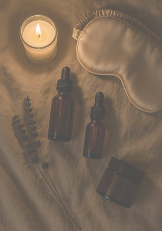 A lit candle, a soft eye mask, lavender and treatment oils
