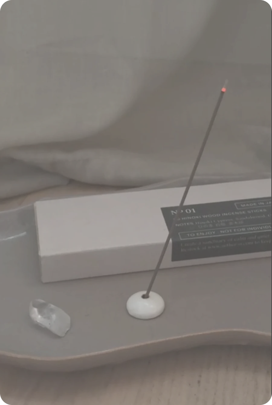 A glowing incense stick on a tray beside the treatment bed